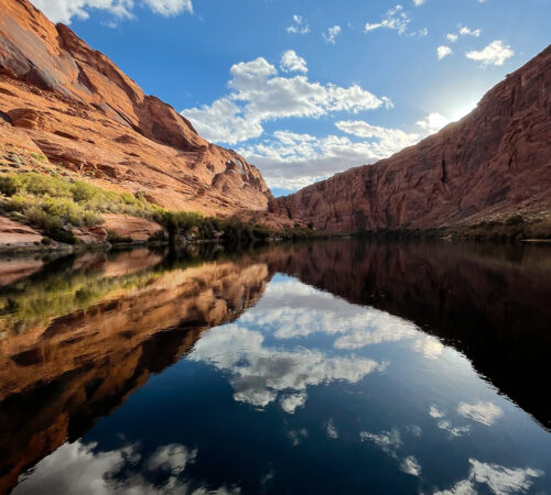 Reflections of cliffs and clouds in the Colorado River in Glen Canyon, AZ